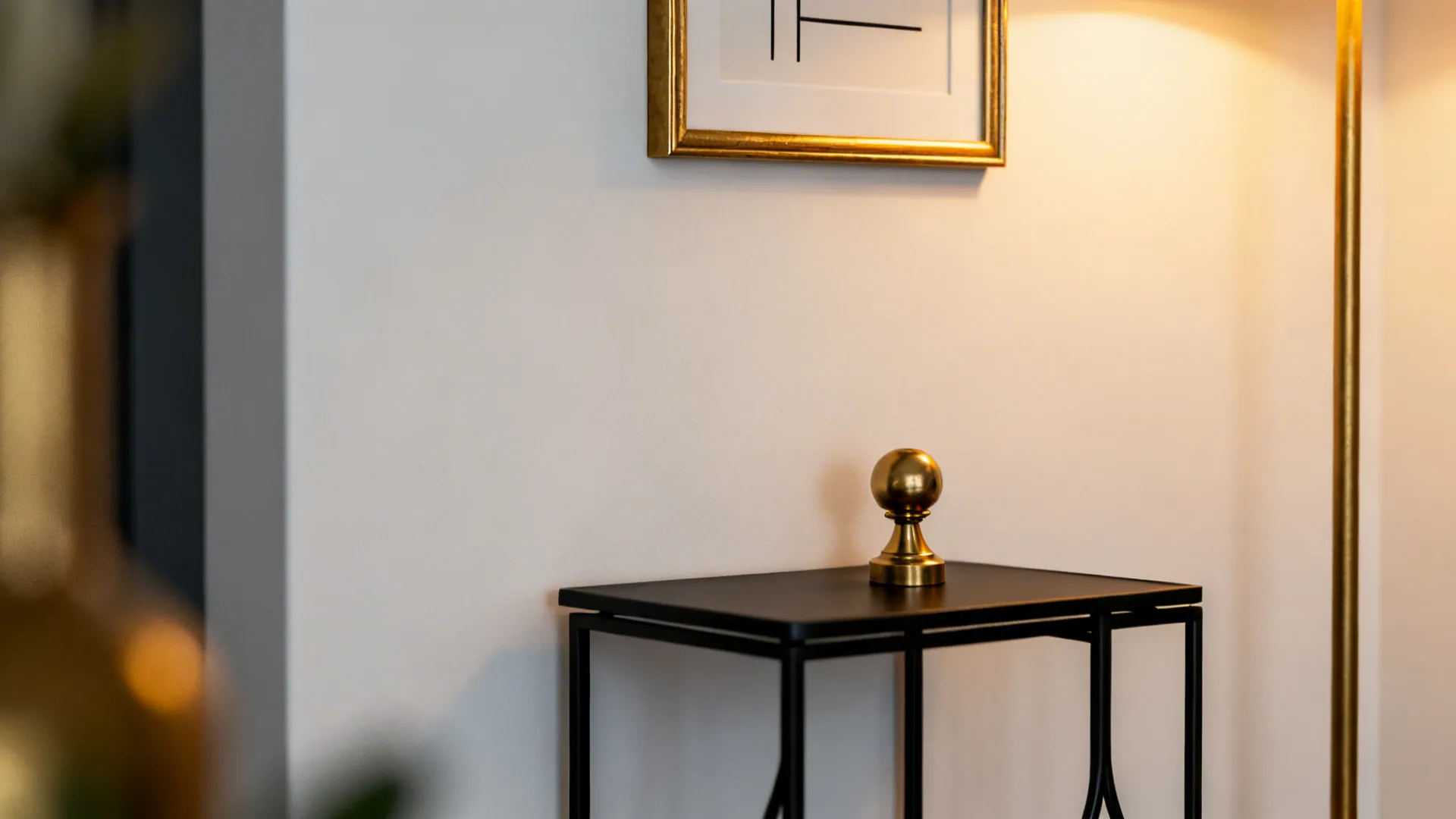 Black side table with gold decorative ball and warm wall light in modern house interior