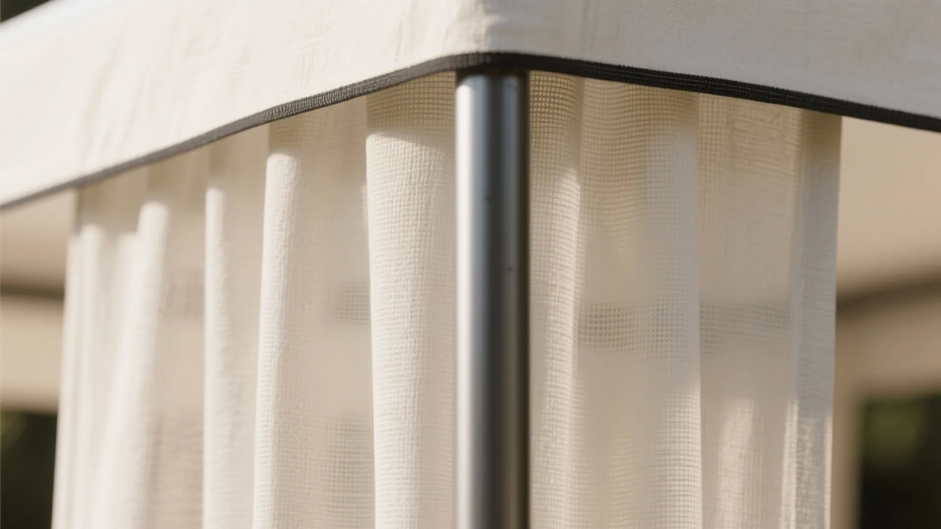 Macro detail of sheer linen canopy fabric over a slim matte metal post, softly lit in warm white tones.