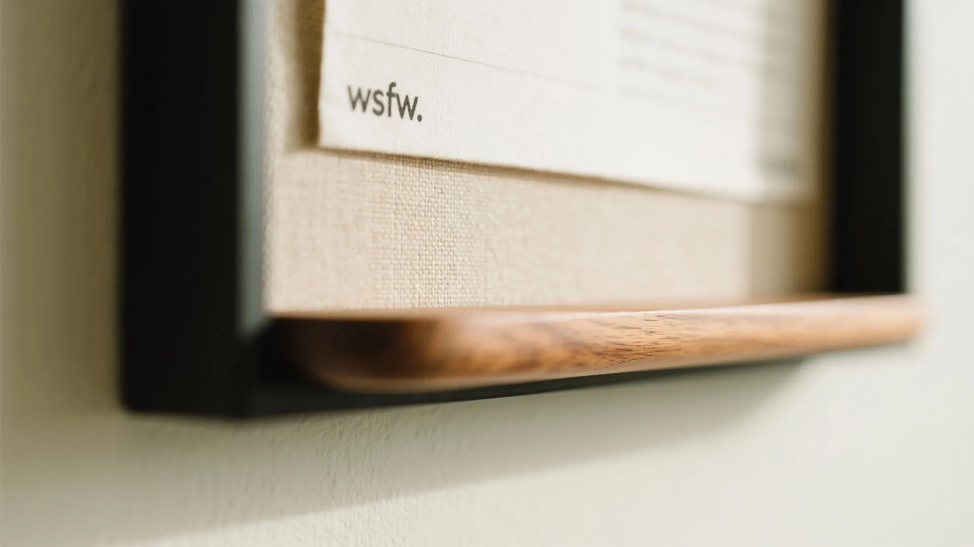 Close up of black picture frame with fabric background and a thin wooden bottom shelf