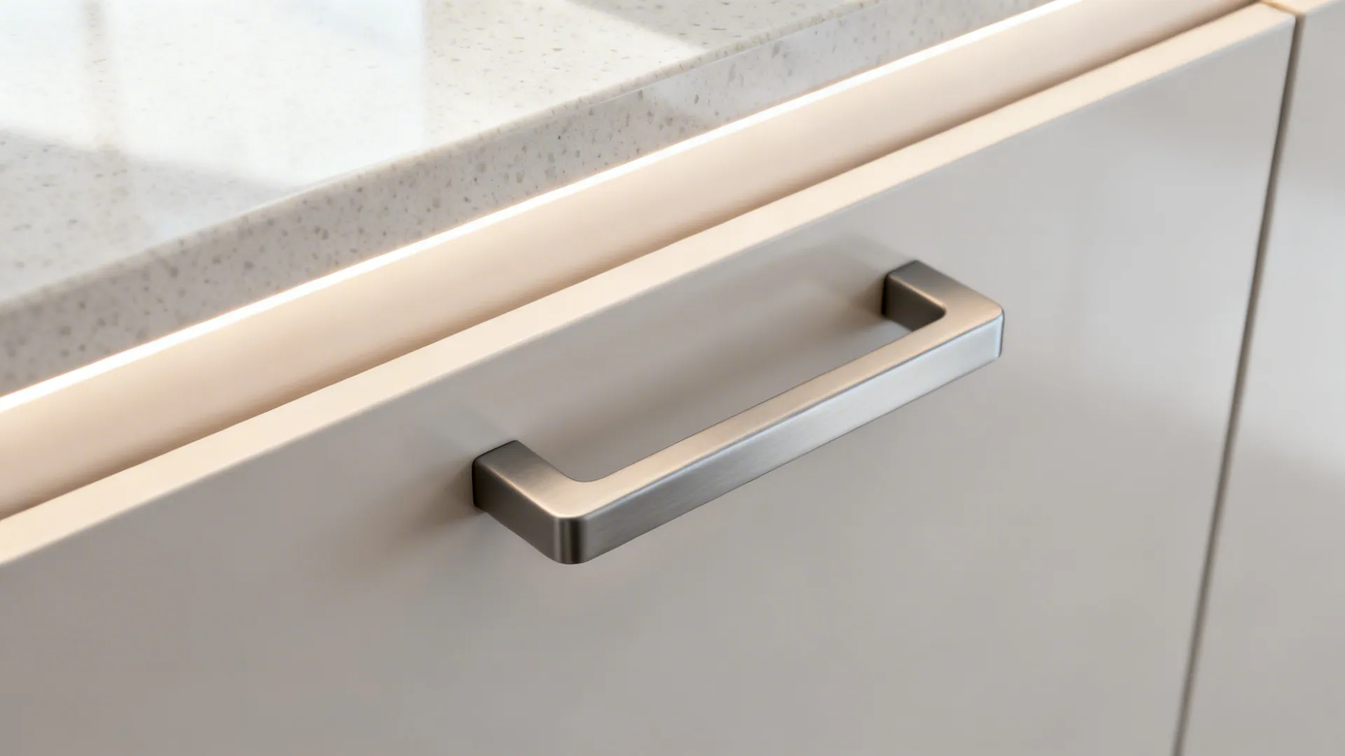 Close-up of powder-coated handle on a satin cabinet next to pale quartz.