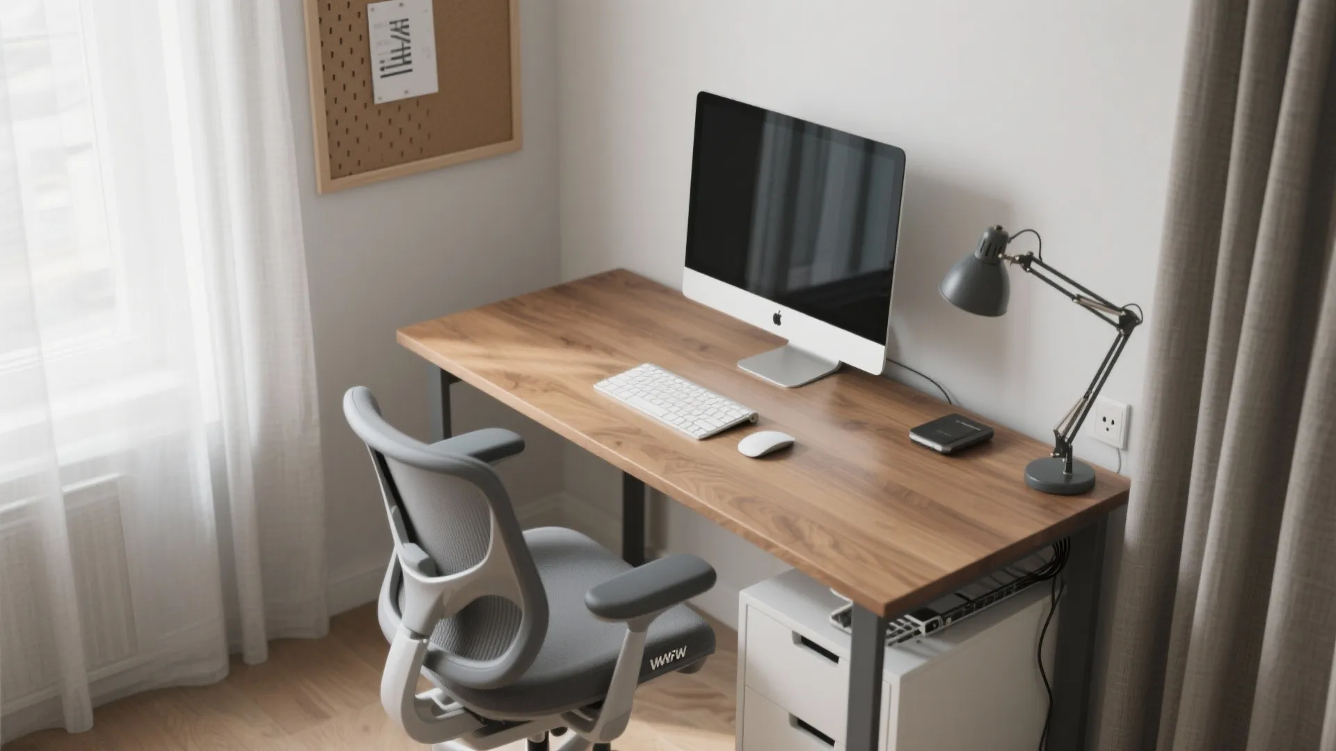 Clean workspace showing wood desk with computer, grey ergonomic chair, and desk lamp near window