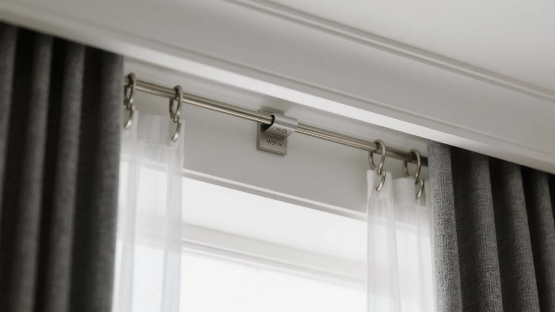 Close up of metal curtain rod with rings holding white sheer and grey blackout curtains