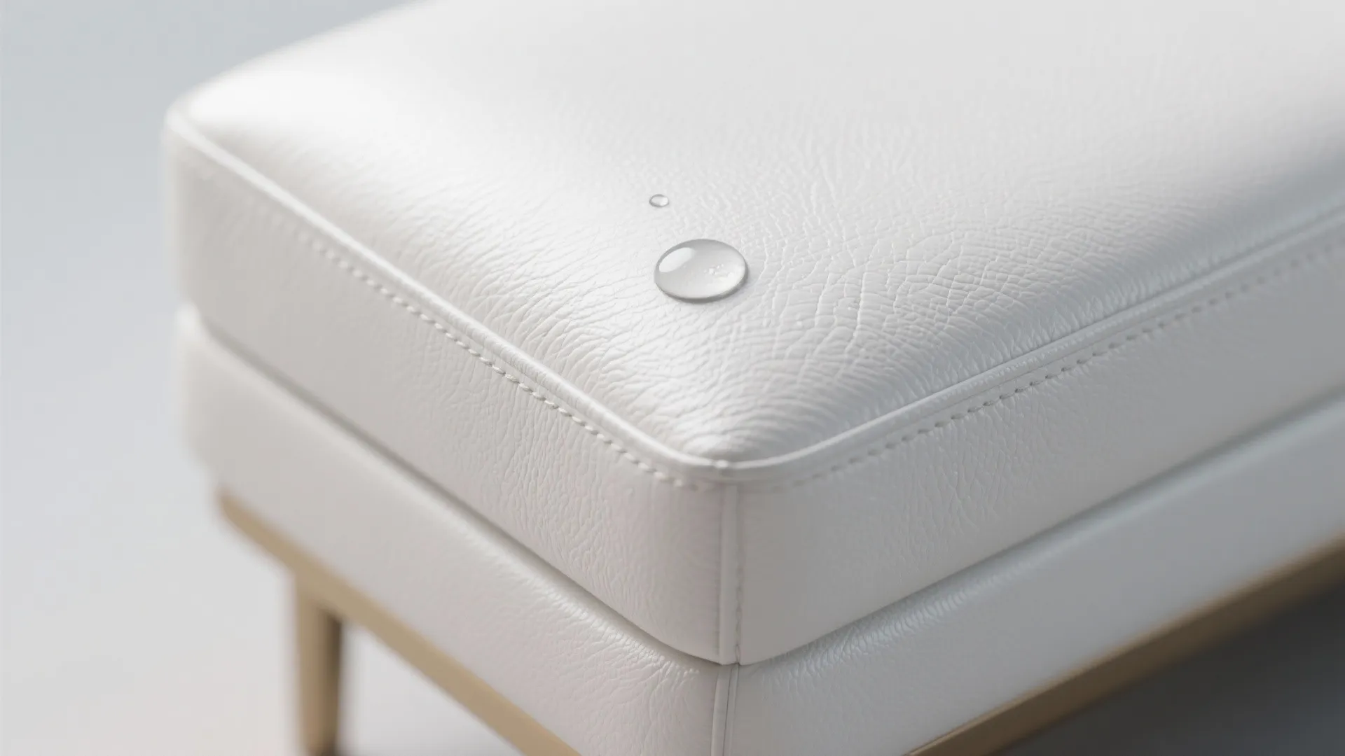 Close up of water drops on a white leather sofa surface showing waterproof fabric material