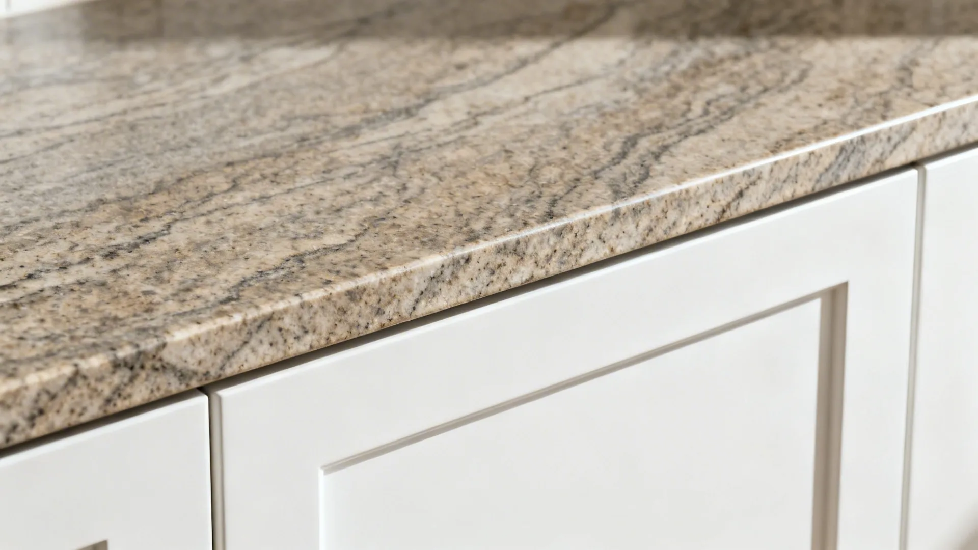 Macro detail of Fantasy Brown Granite eased edge over a matte white cabinet face.