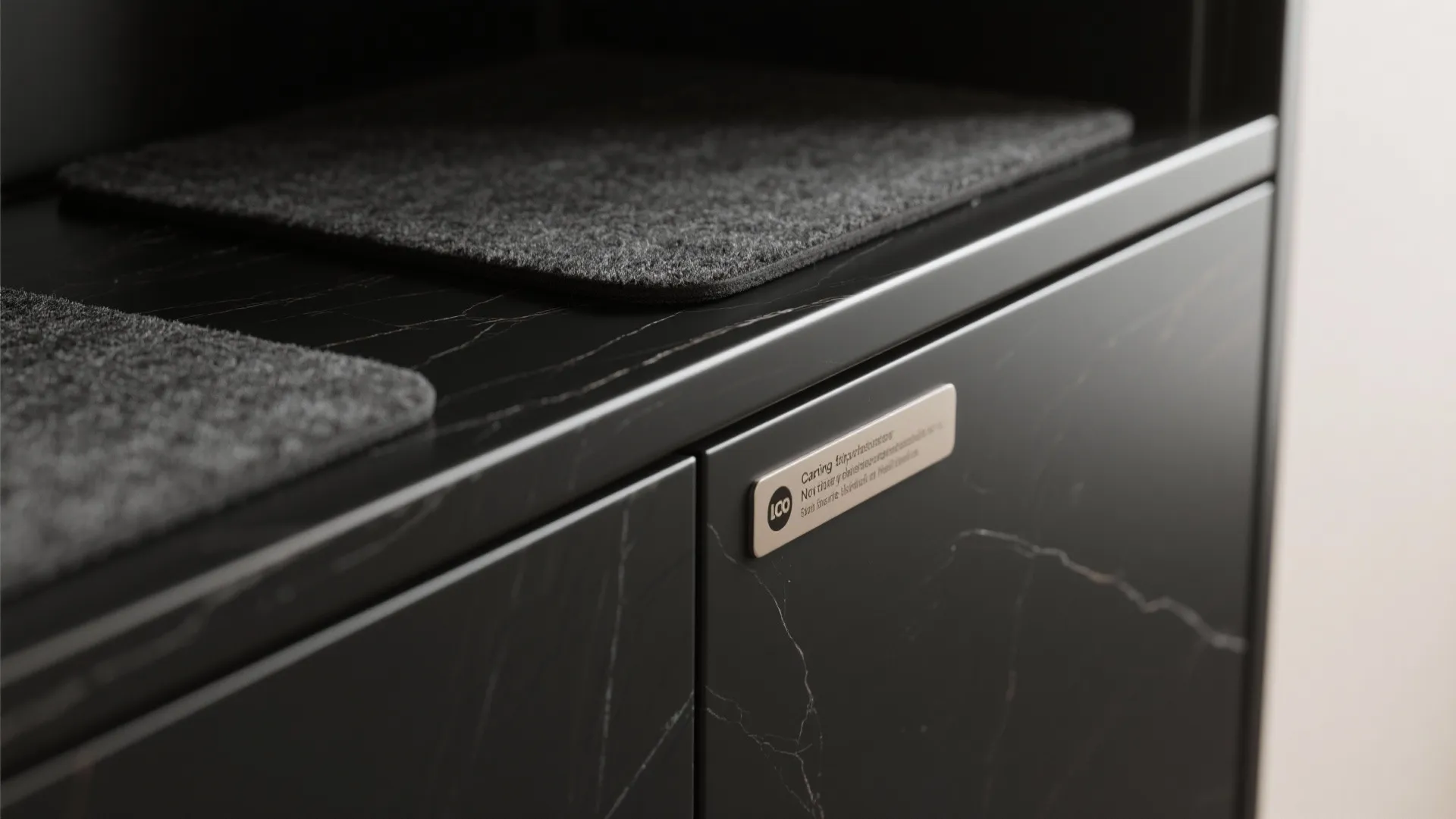 Close up of black marble cabinet with instruction label and grey felt mats on top surface
