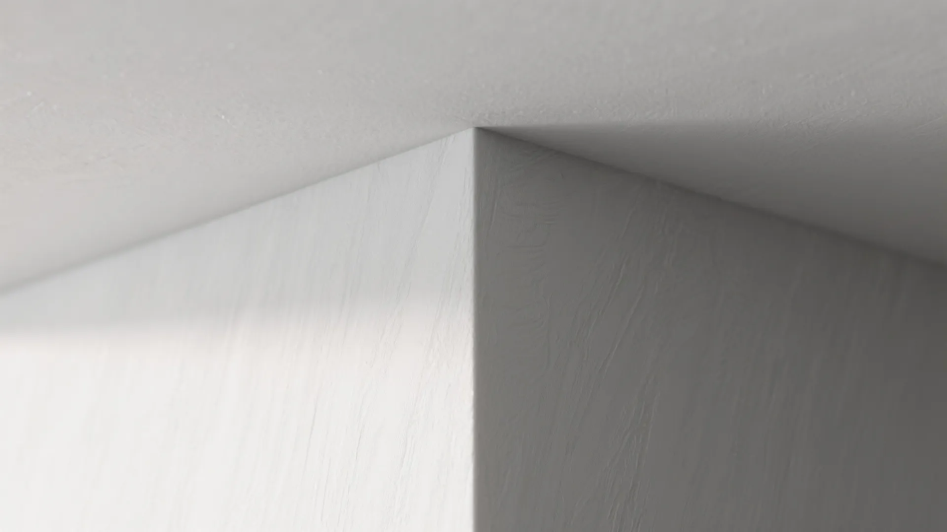 Close up of a sharp white wall corner showing smooth plaster finish and subtle lighting