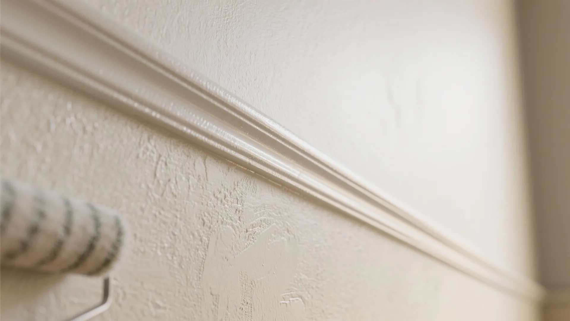 Close up of a beige wall panel with smooth texture and a paint roller tool