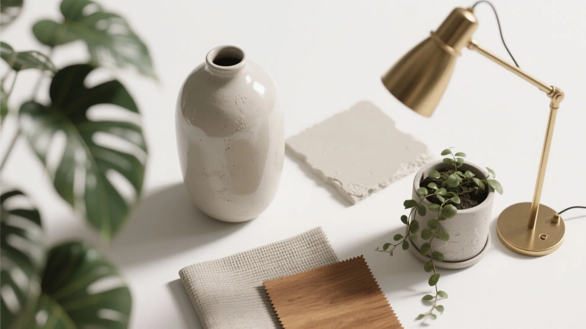 Beige vase gold desk lamp small green plant fabric samples stone piece and green leaf decor