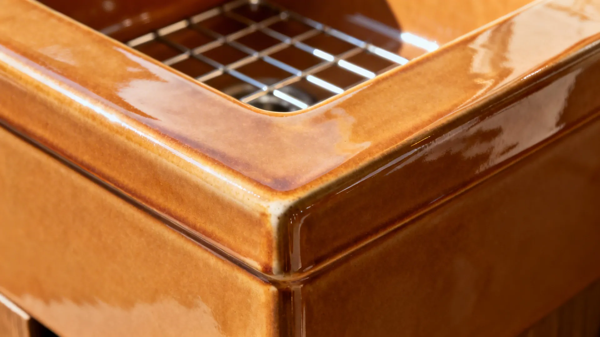 Macro of a squared fireclay apron-front edge with glossy glaze and bottom grid.