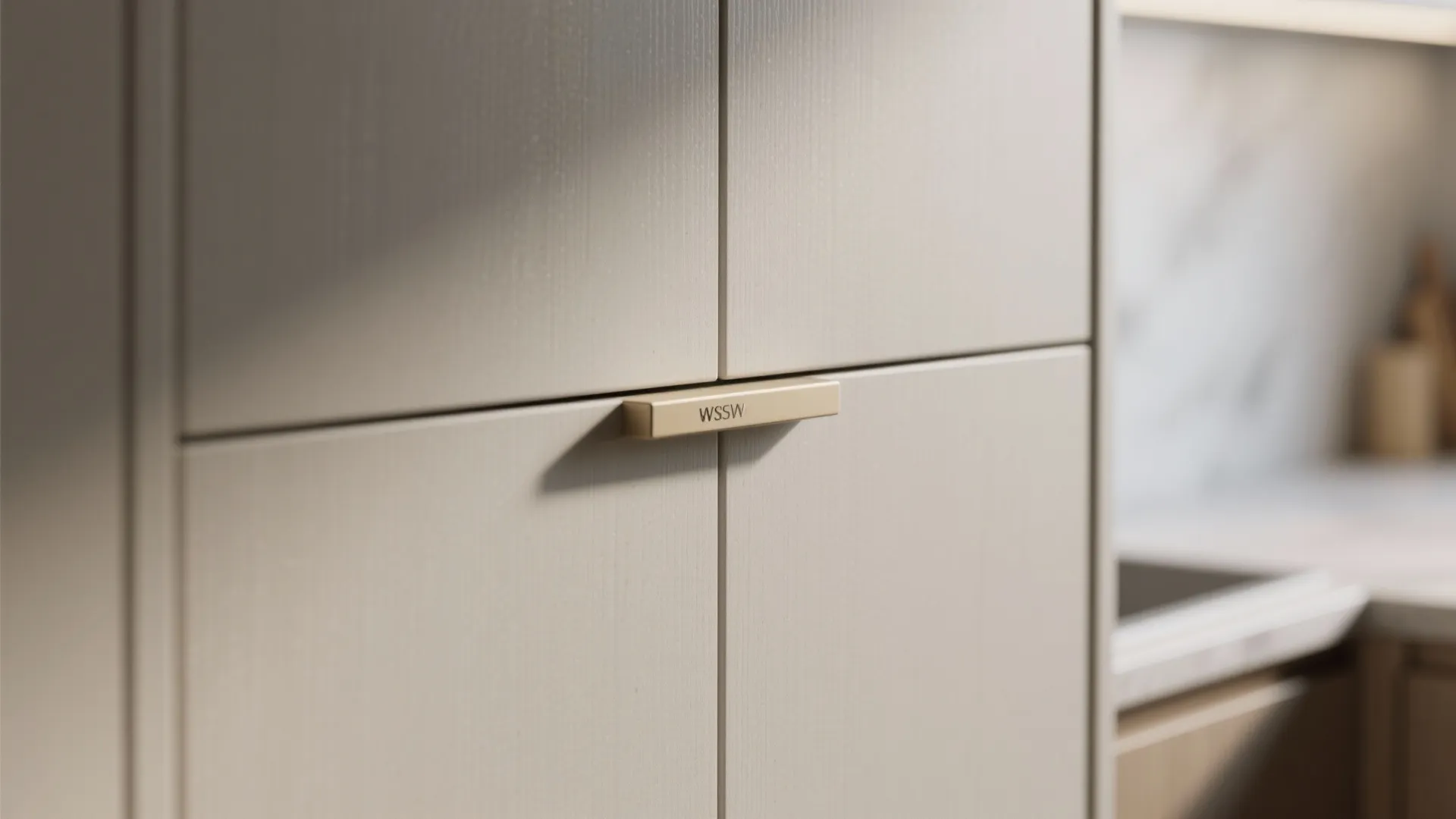 Close up view of light grey kitchen cabinet door with a gold handle and soft lighting