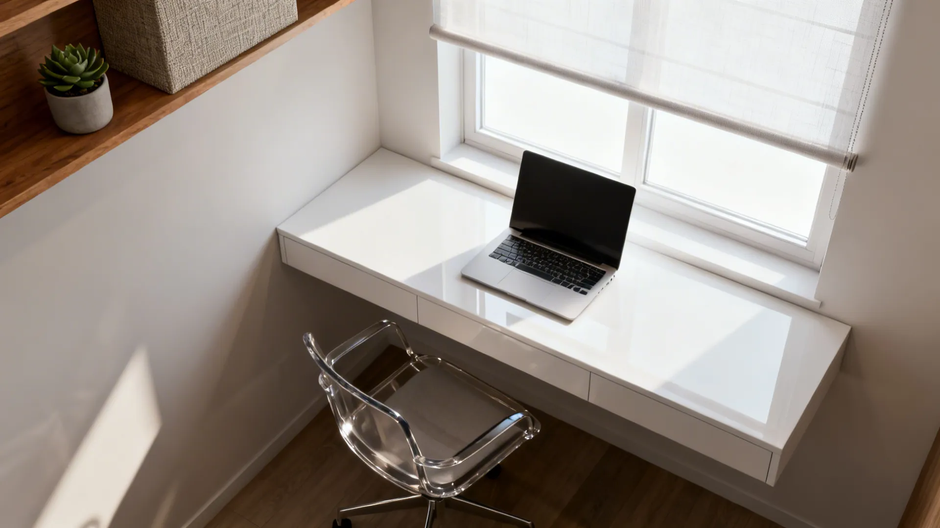 Compact floating desk under a window with a sheer blind and chair showing clear circulation space.