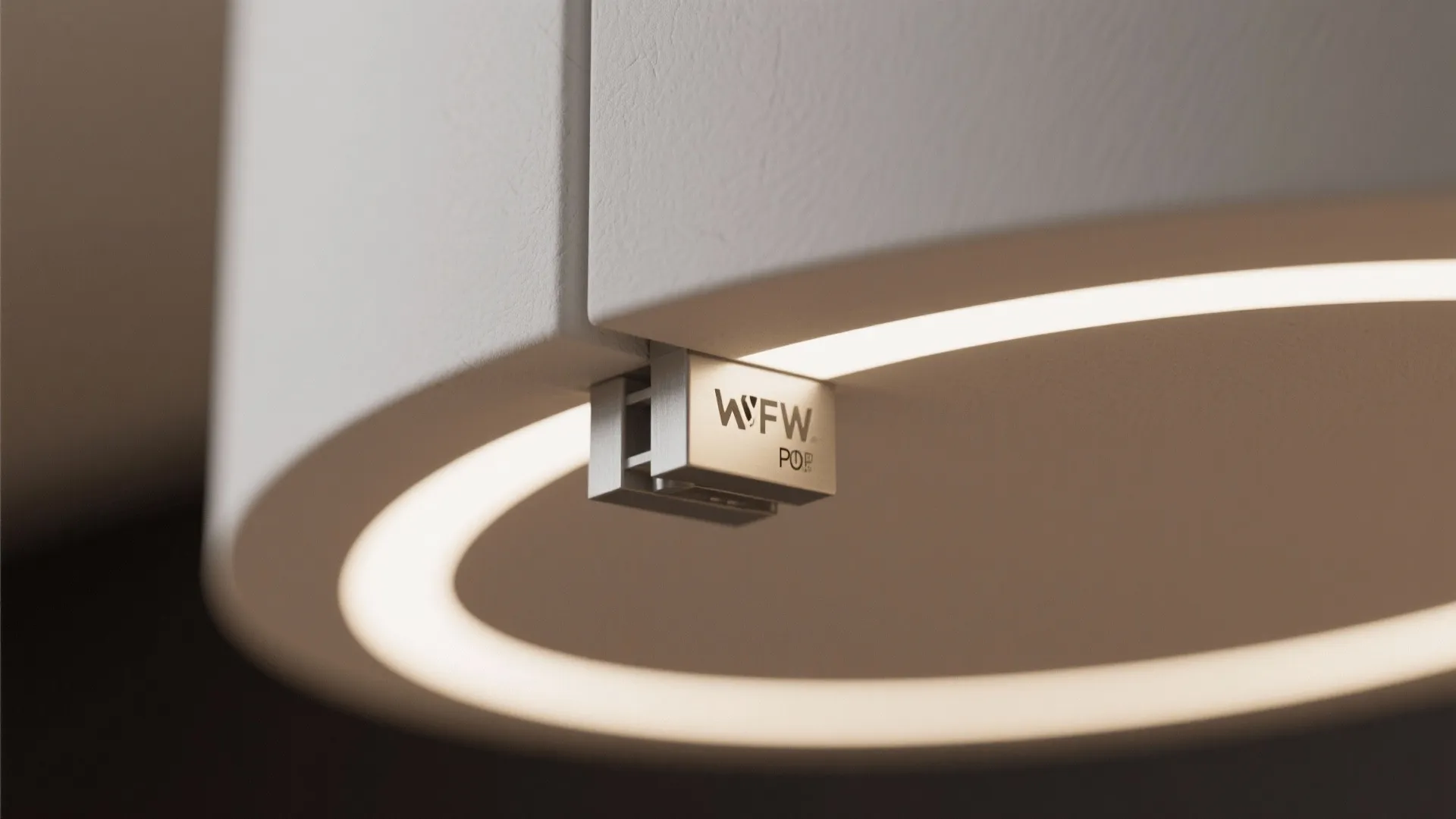 Close up of a white light fixture with round glowing ring and metal brand label