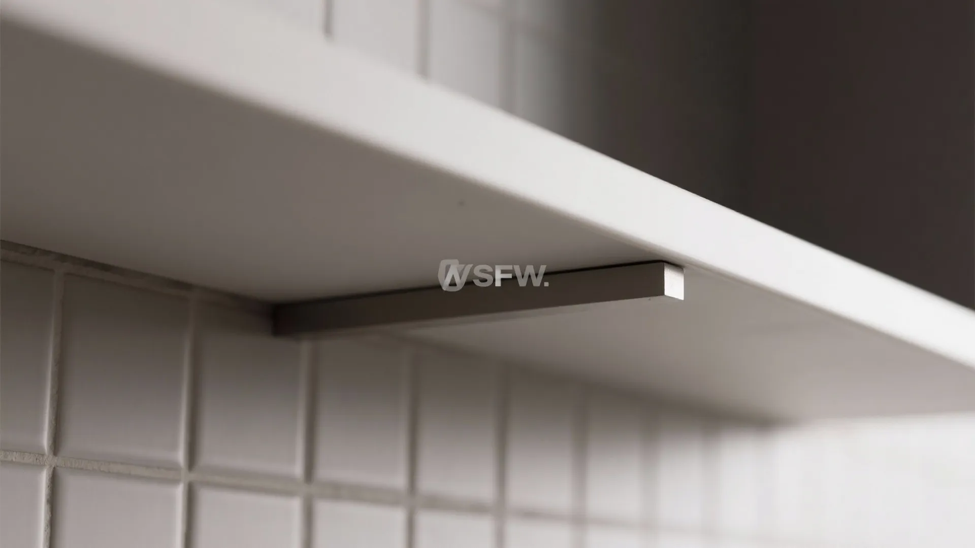 Close up of a white floating shelf with a metal bracket installed on white wall