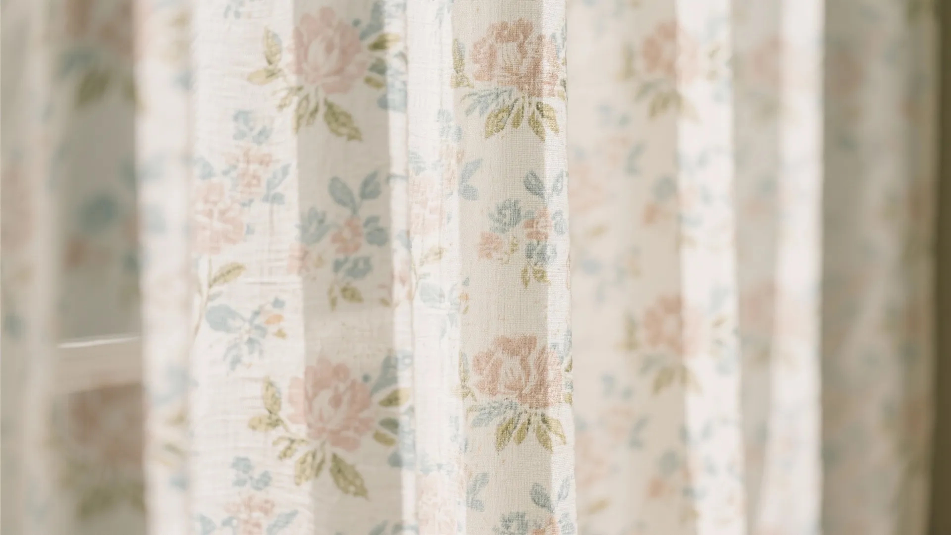 Close up of a cream white curtain with soft pink and blue floral pattern details