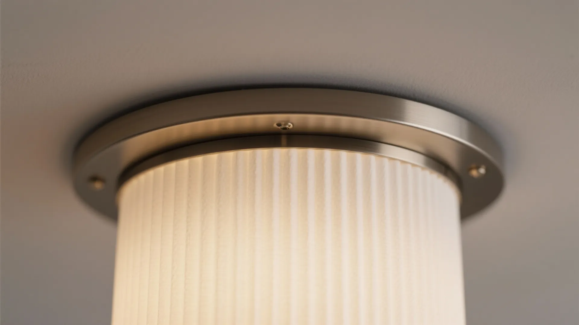 Close-up of pleated drum chandelier with matte opal diffuser and metal trim.