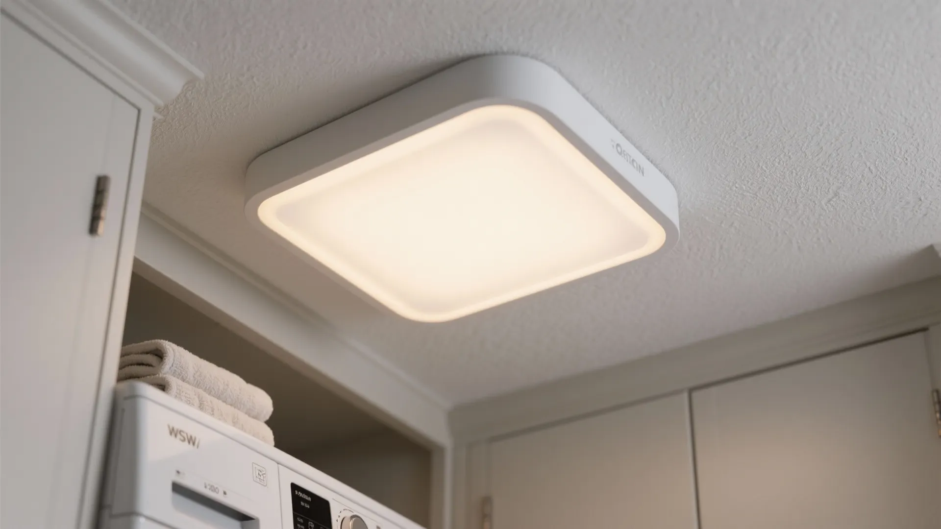 Modern white square ceiling light fixture installed on a white ceiling above a laundry room area
