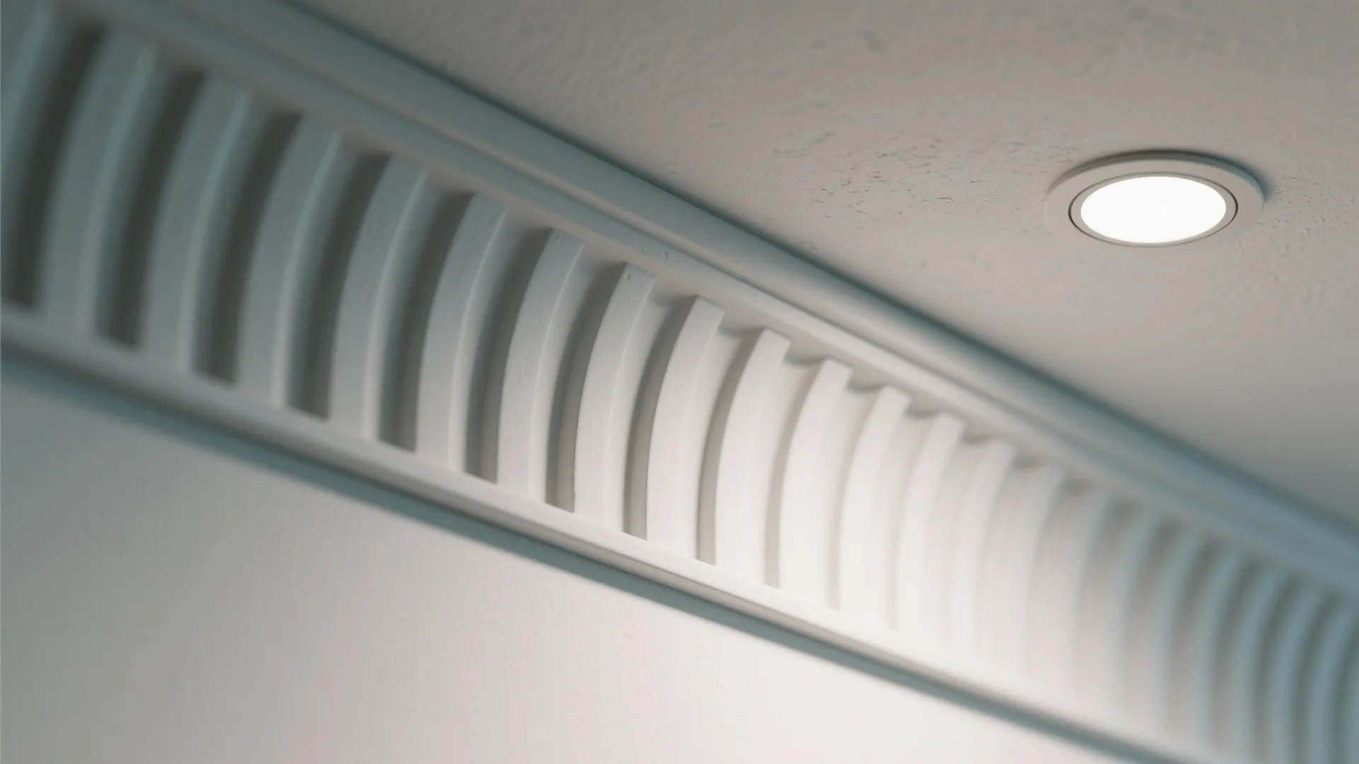 Close up of white wall panel trim on ceiling with a small round recessed light
