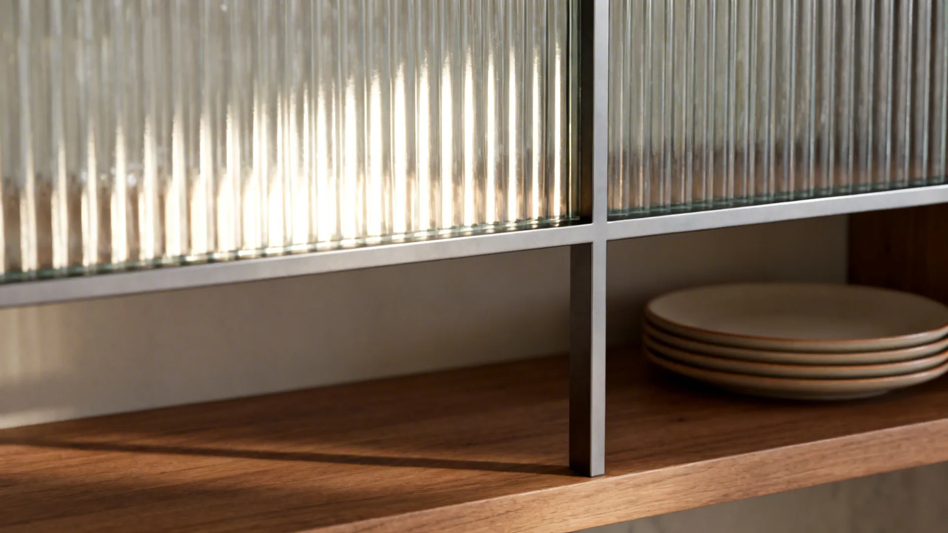 Close-up of fluted glass divider and oak shelf with stacked plates.