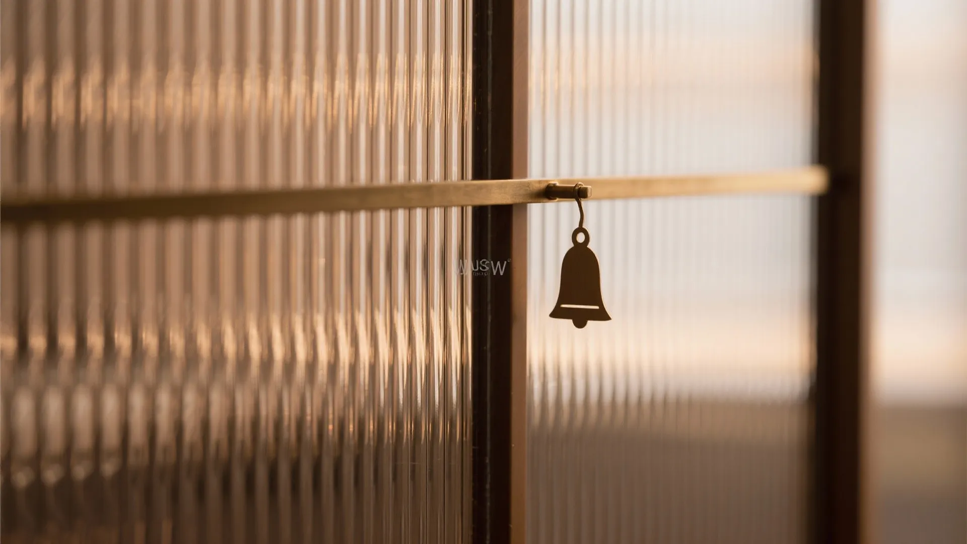 Macro of bronze-tinted fluted glass sliding door with a subtle bell motif and brass track.