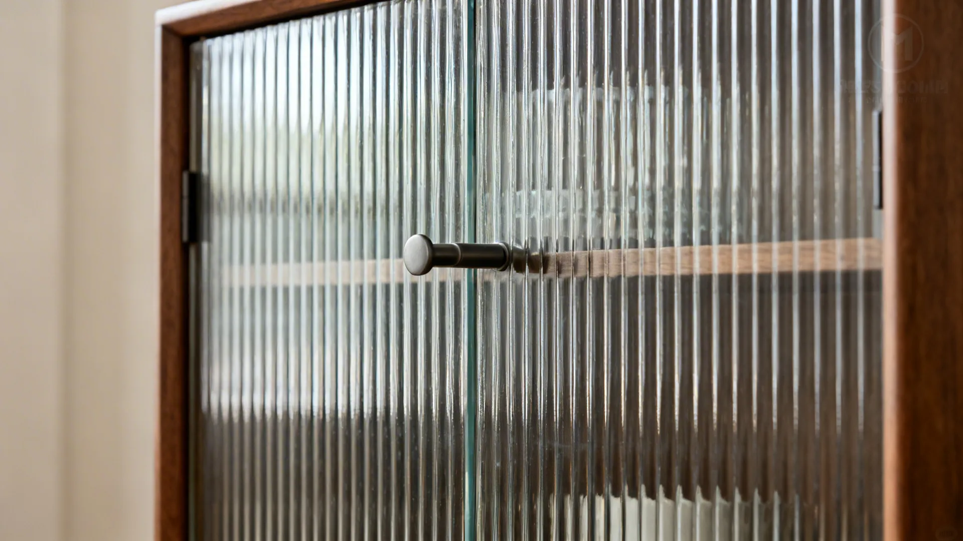 Close-up of fluted glass cabinet door with matte metal handle and warm wood frame.