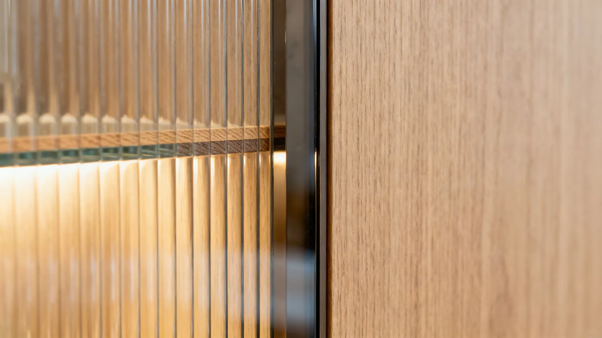 Close up of ribbed glass cabinet door with inner light fixture next to wood grain