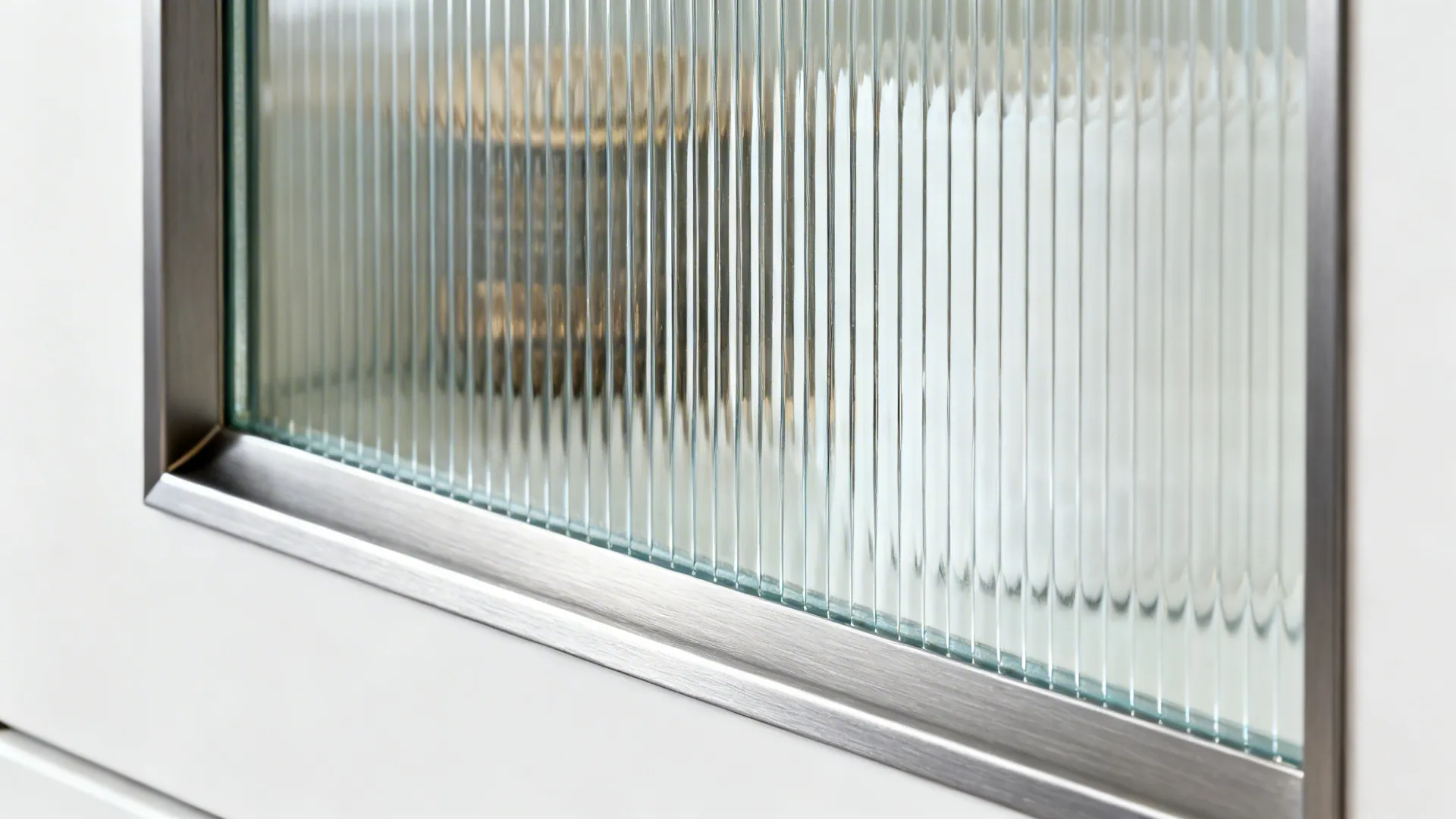 Close-up of fluted glass ribs in a slim metal cabinet frame.
