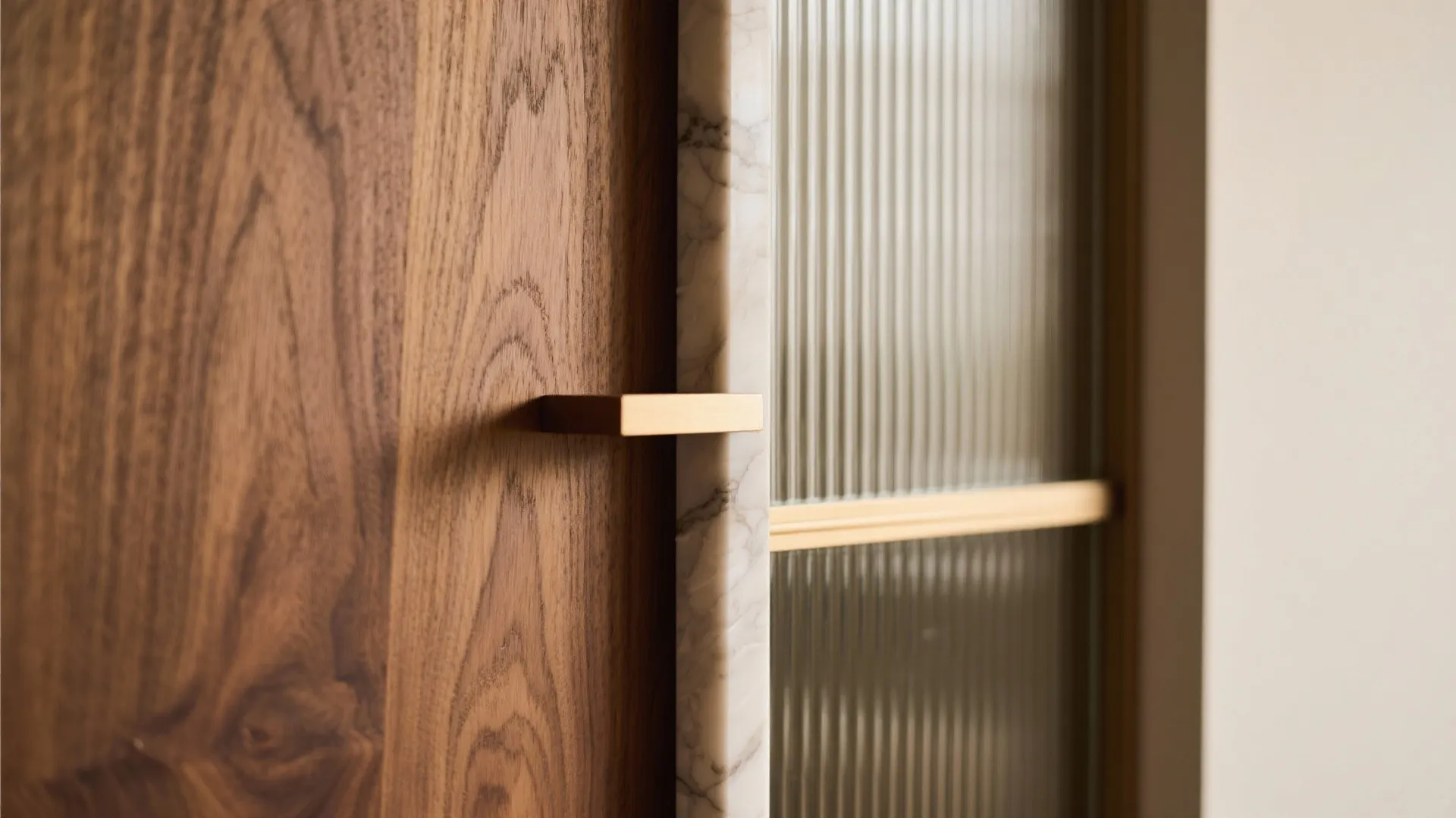 Close-up of wooden door with marble edge textured glass panel and a gold metal handle