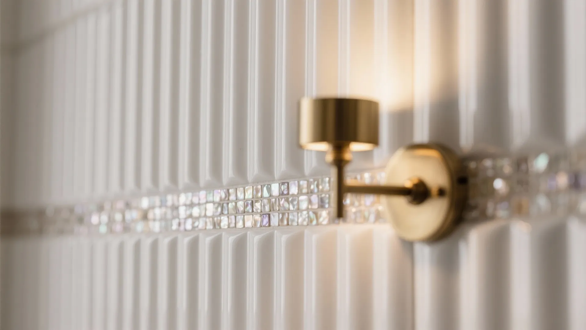Golden wall light mounted on a white wall panel with a decorative mosaic tile stripe