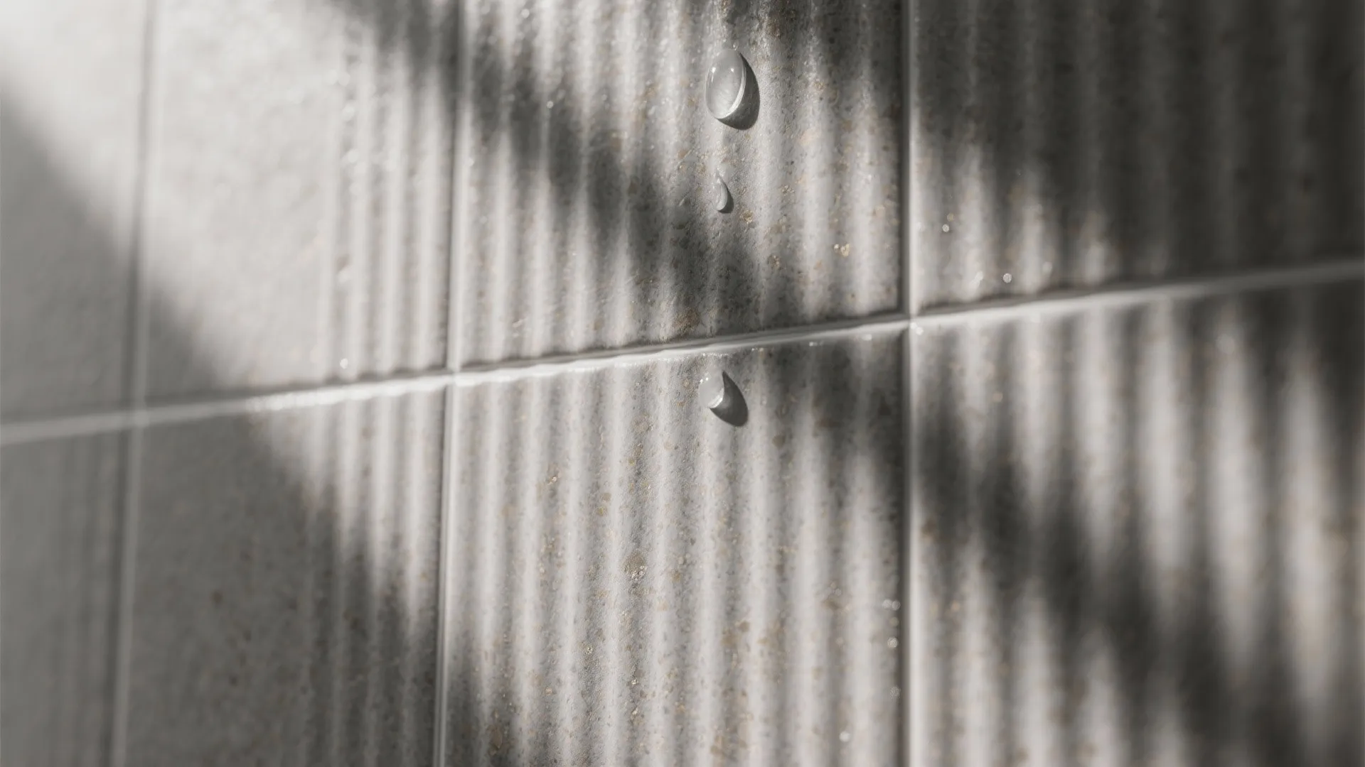Macro of fluted gray tile with soft daylight highlighting fine grooves and matched grout.