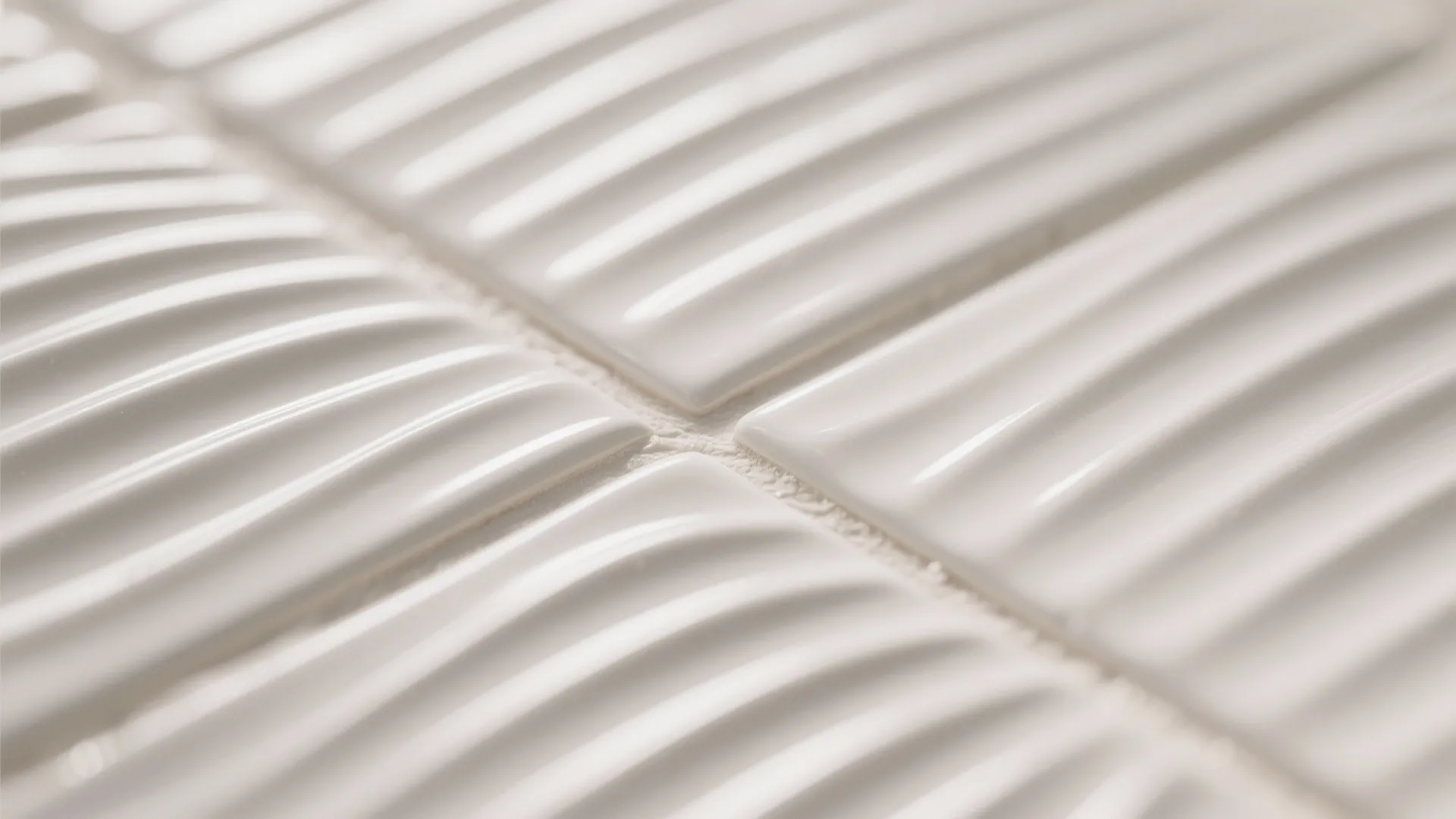 Macro of fluted white tile with gentle ripples highlighted by grazing light.