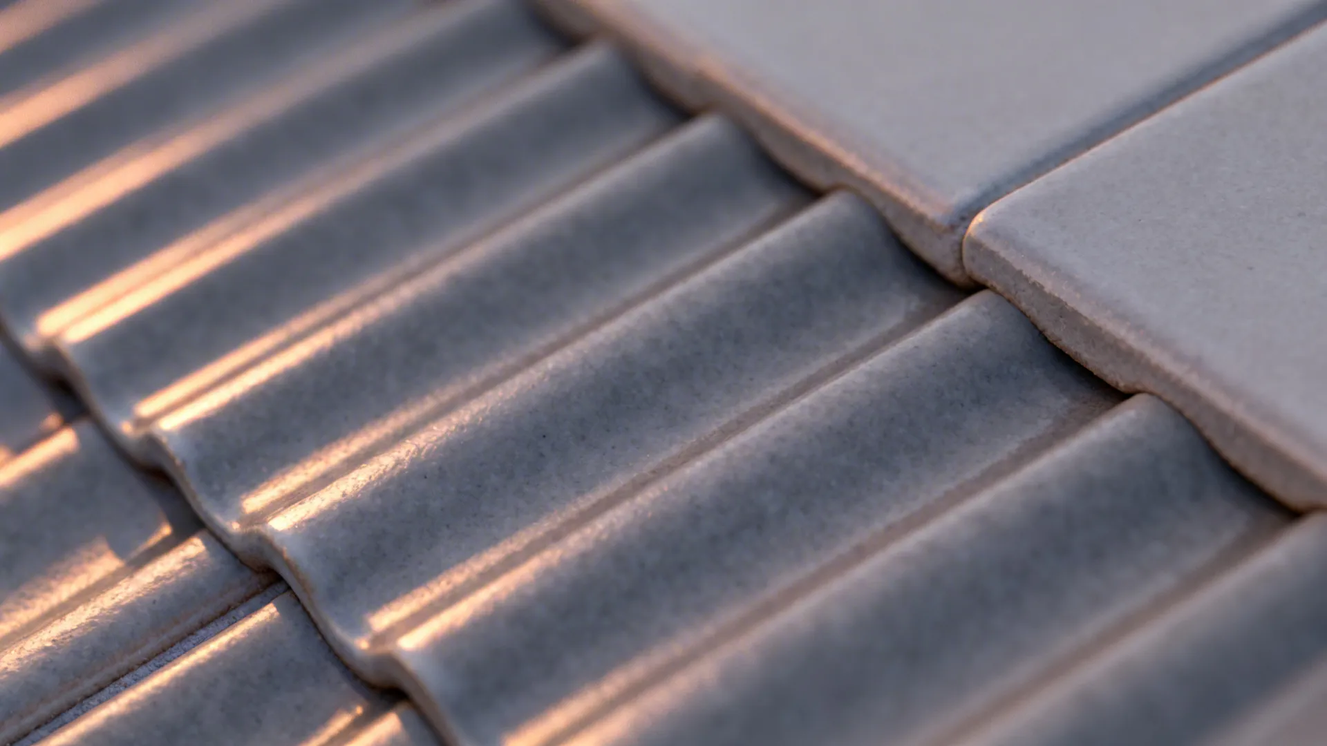 Macro detail of fluted grey tile with raking light highlighting ridges and glaze.