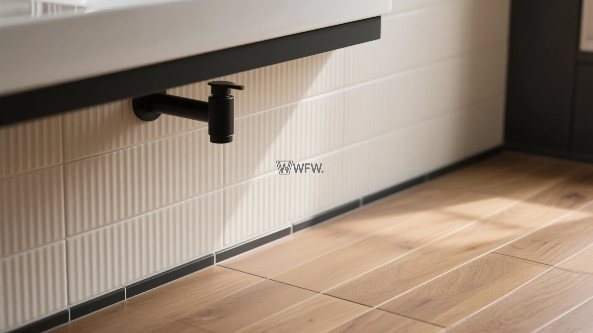 Close up of white wall panel with black water tap and light brown wood floor
