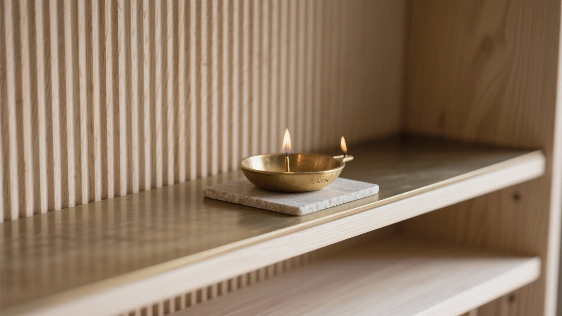 Macro of fluted ash wood and brushed brass diya shelf with stone pad.