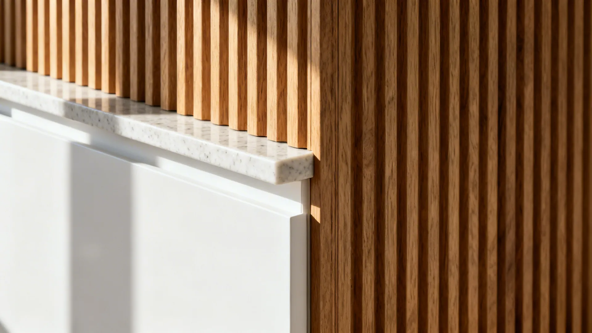 Macro of fluted wood panel beside matte white laminate and quartz countertop edge.