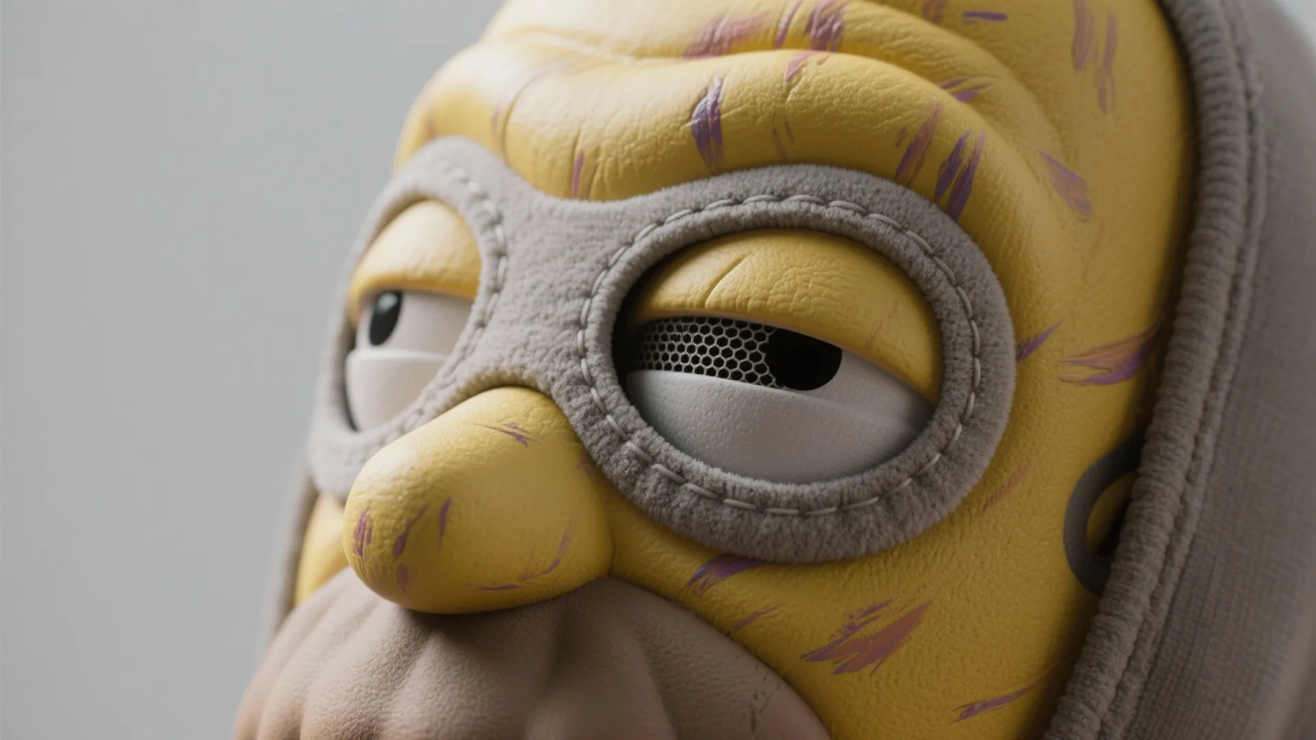 Yellow textured mask with purple scratches and gray fabric stitched around the large round eyes