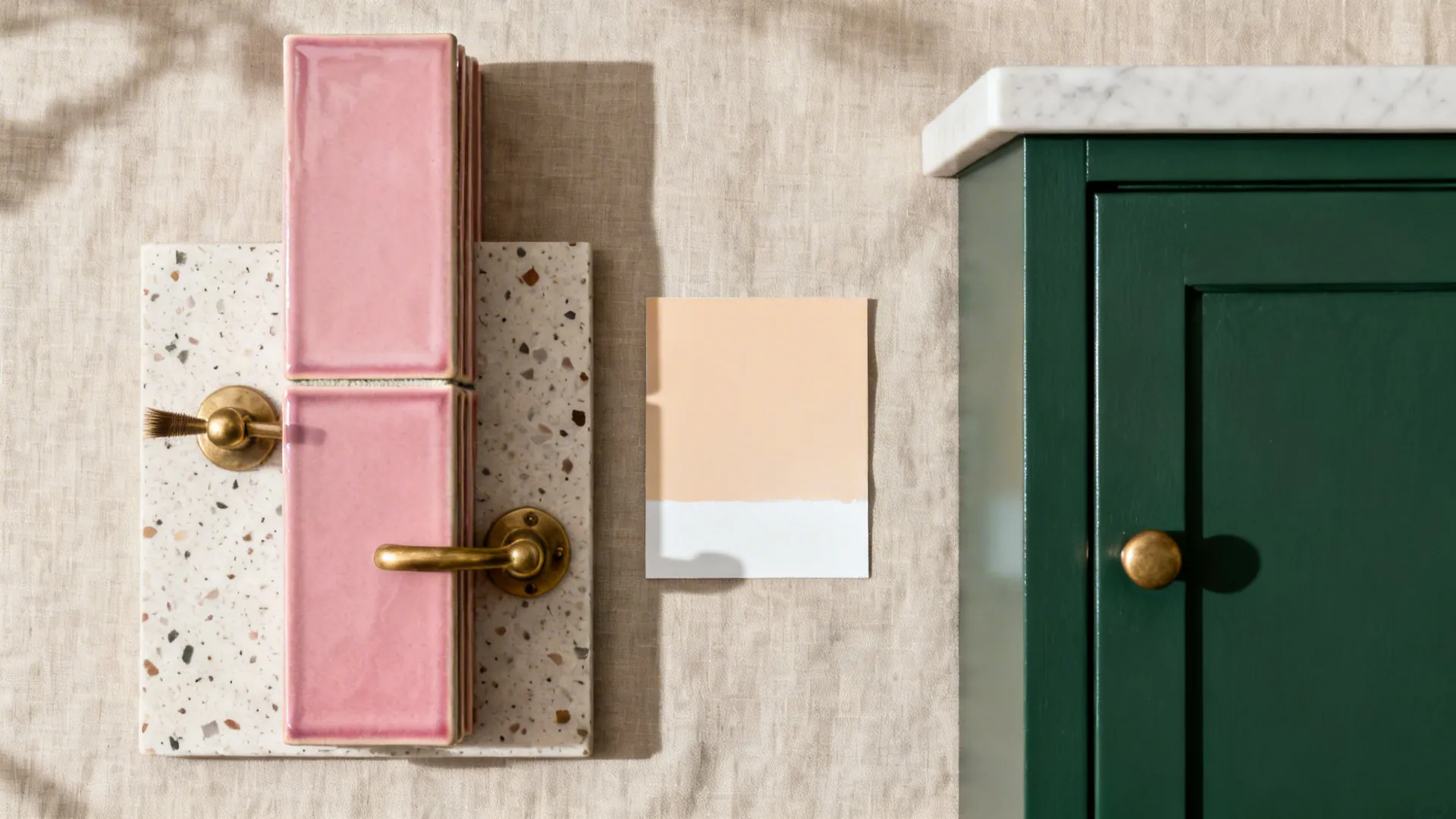 Top-down flat lay of forest green sample, pink tiles, terrazzo, and brass hardware.