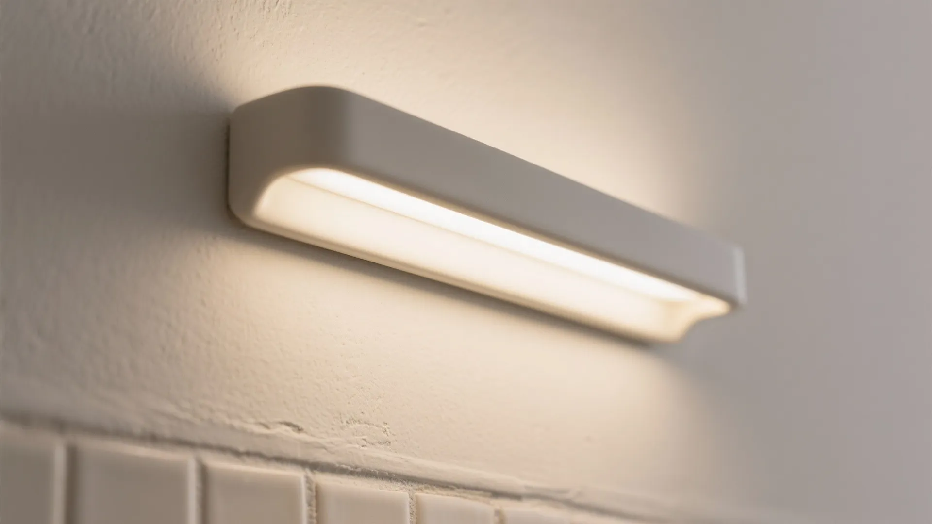 Close up of a sleek white wall light fixture mounted on a neutral textured wall