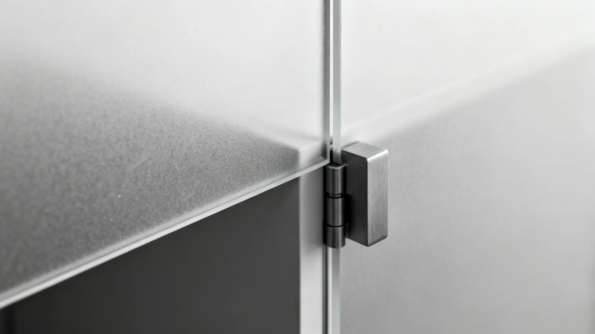 Detail view of a metal hinge attached to a frosted glass door of a modern cabinet