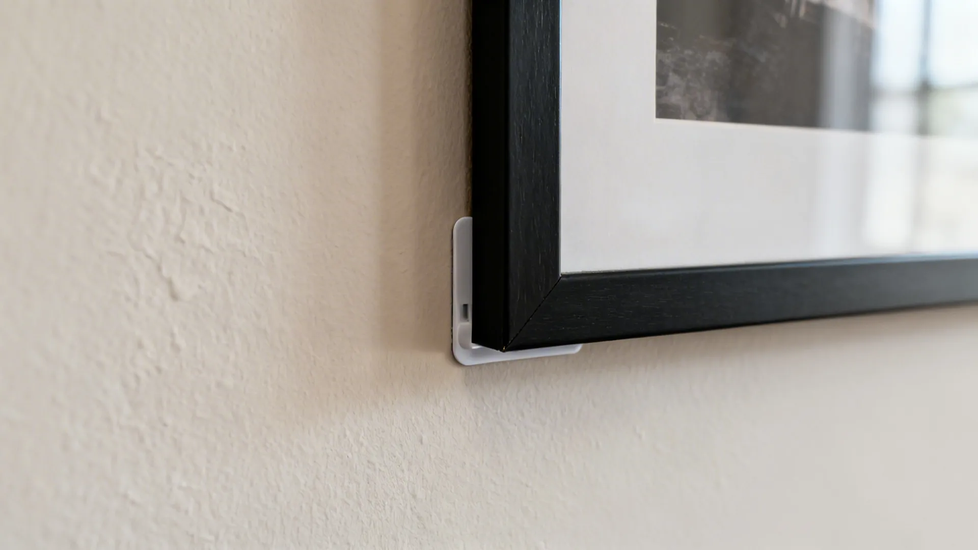 Close-up of neatly spaced black frames on a neutral wall with clean mounting detail.