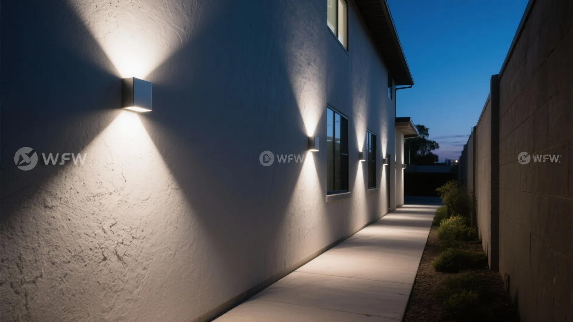 Square silver wall lights creating bright light patterns on white exterior house wall near concrete path