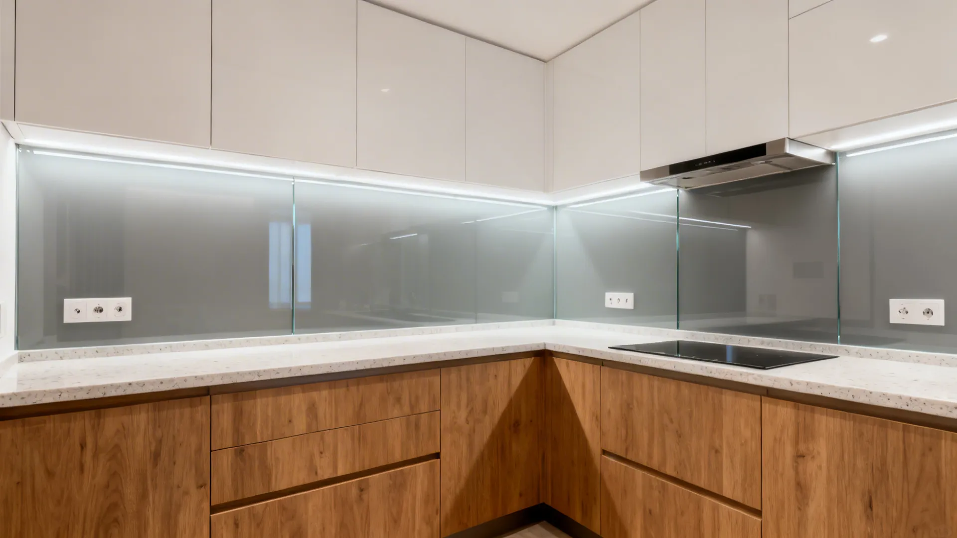 U-shaped kitchen with a full-height gray-tinted glass backsplash that brightens the space.