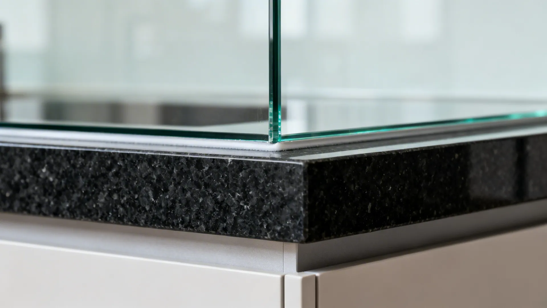 Macro of black granite upstand meeting clear low-iron glass backsplash joint