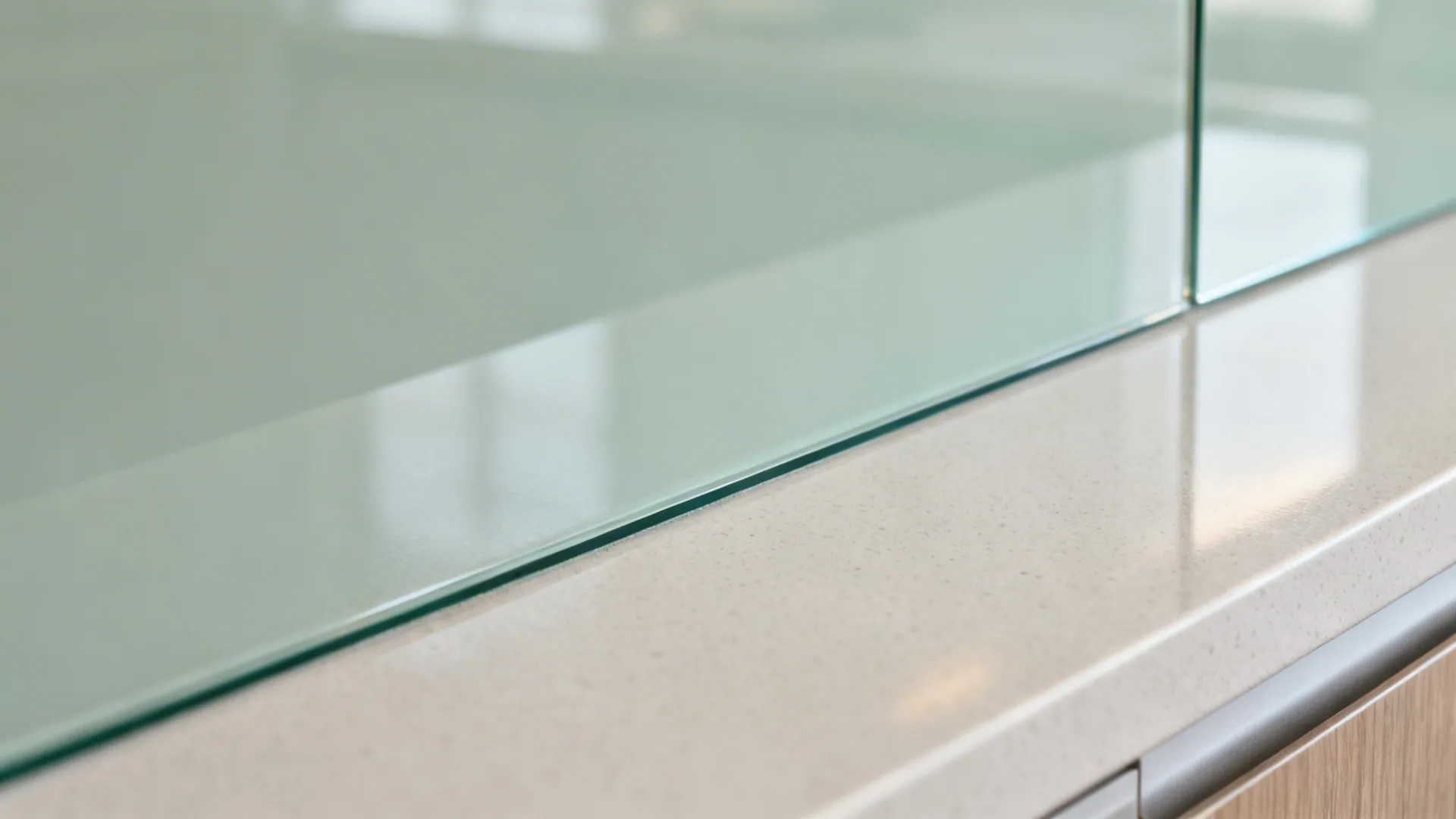 Close up shot of green glass wall edge meeting a clean white stone kitchen counter