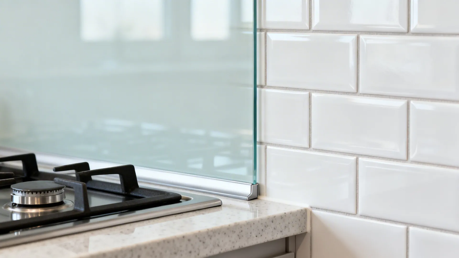 Macro of tempered glass backsplash with satin subway tiles and thin epoxy grout near a hob.