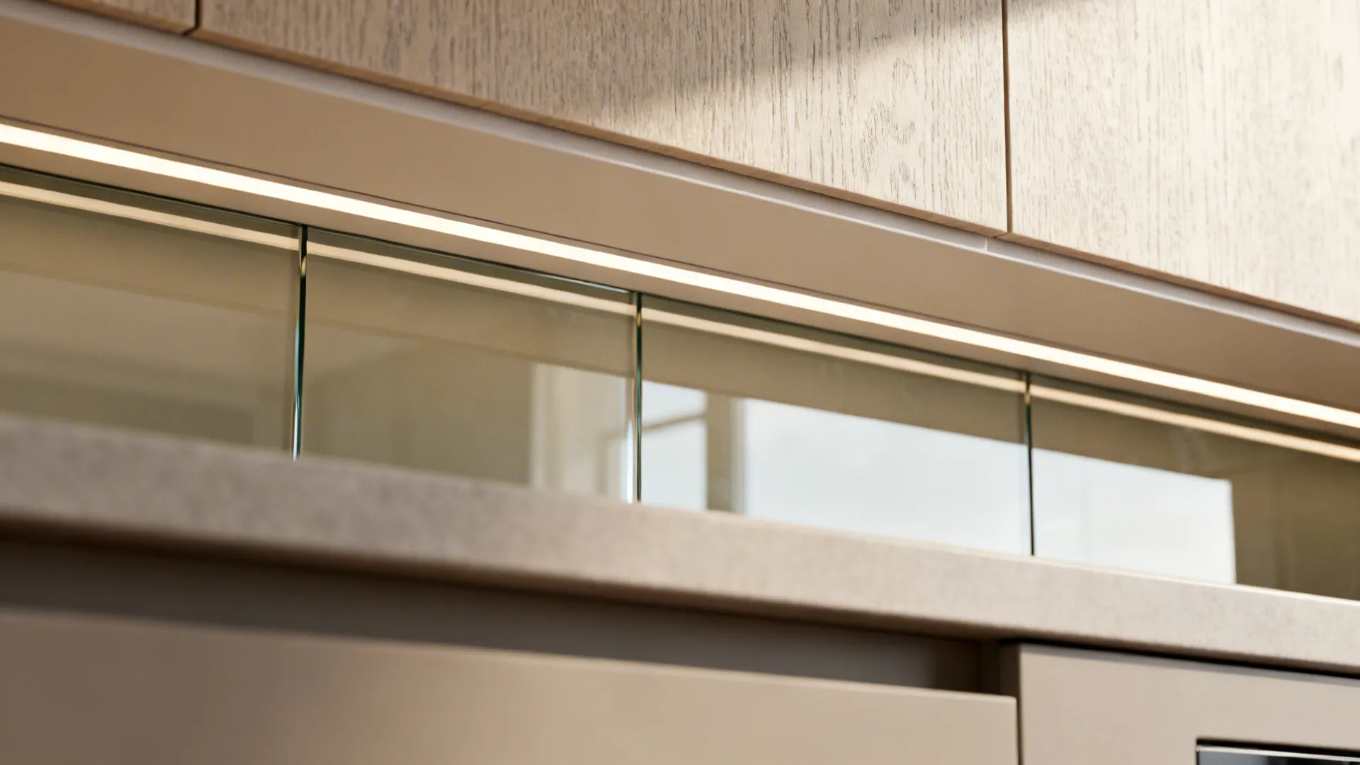 Macro of glass backsplash reflecting LED task light beside matte counter and textured cabinet.