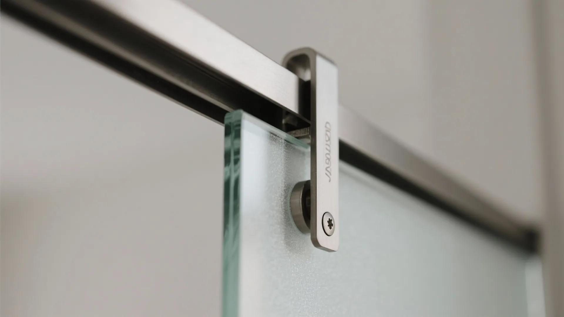 Macro of frosted glass barn door with brushed aluminum hanger and soft-close damper.