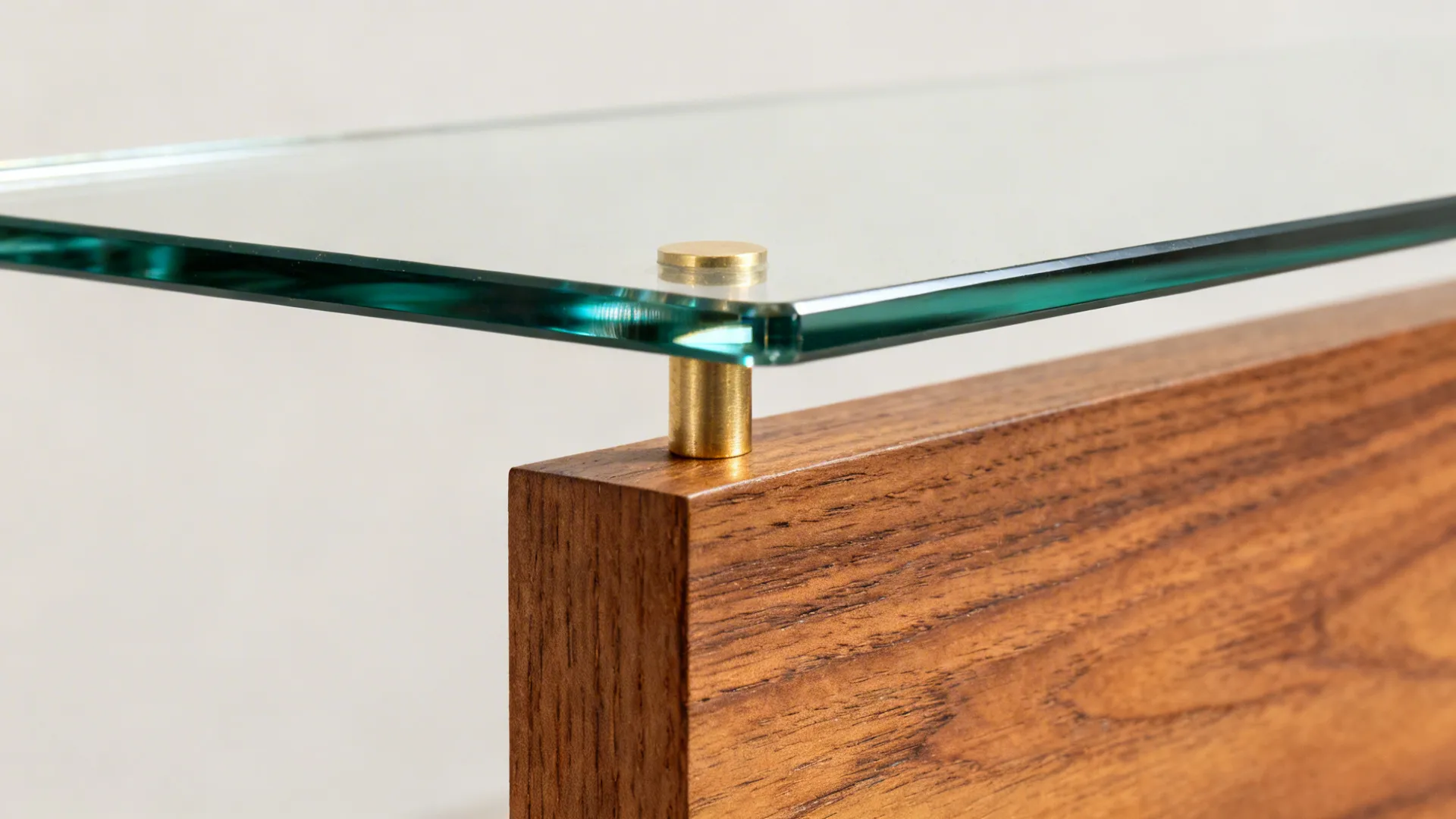 Macro of low-iron glass shelf on a brushed brass pin above warm oak millwork.