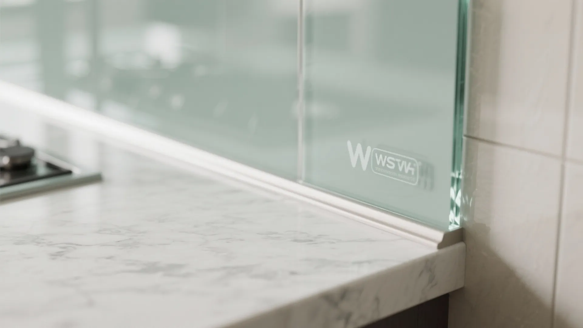 Close up detail of green glass backsplash meeting a white marble countertop in modern kitchen