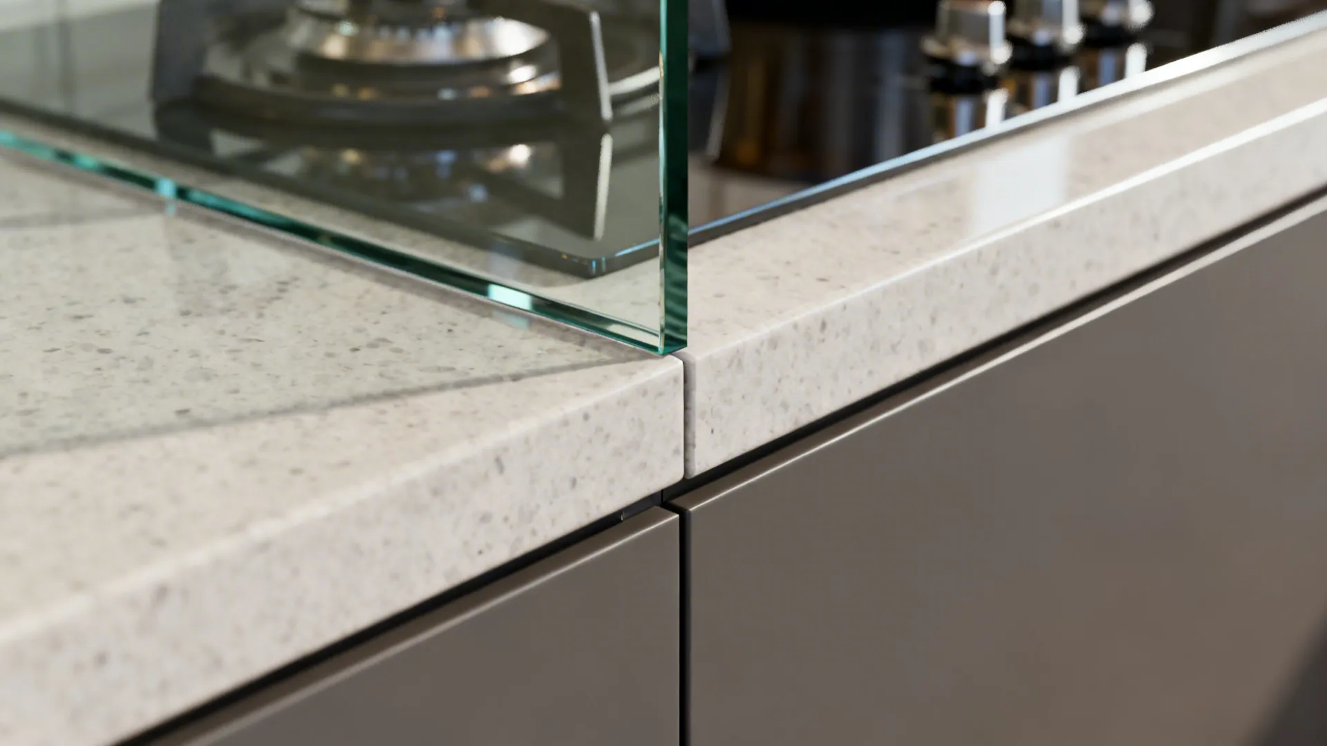 Macro of tempered glass backsplash edge meeting quartz countertop