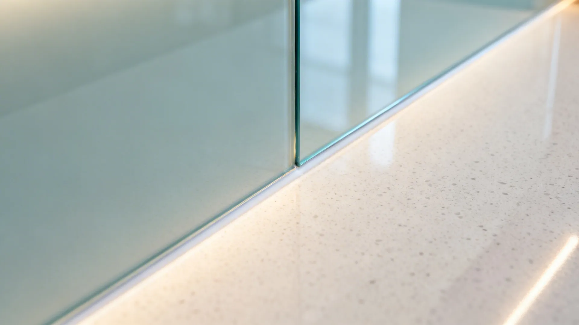 Close-up of back-painted glass backsplash meeting a quartz countertop with clean finish.